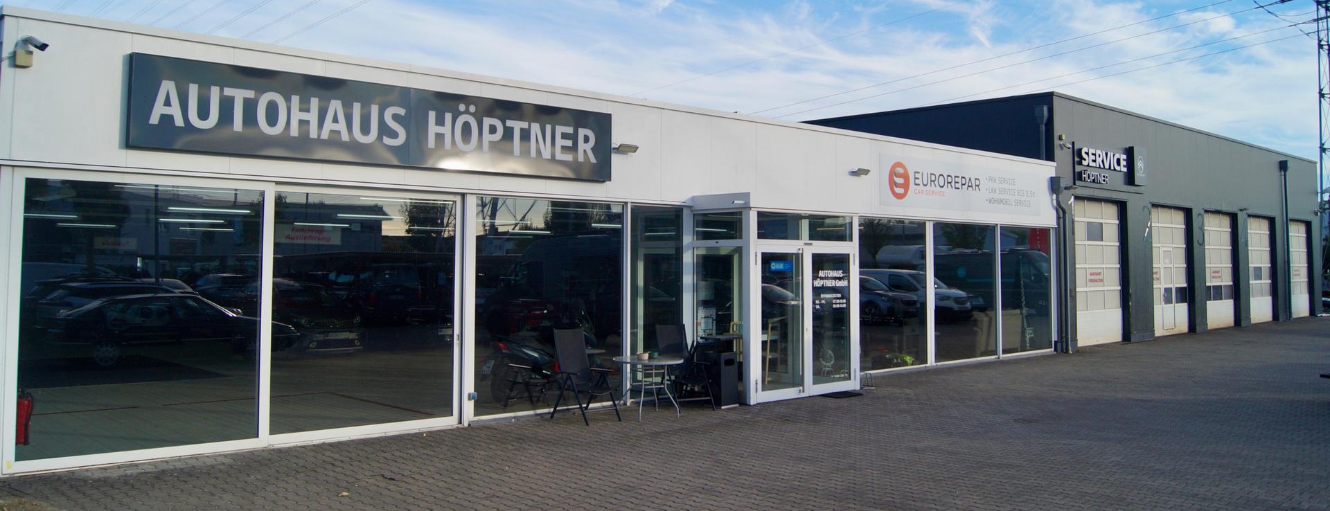 Außenansicht des Autohaus Höptner mit Eingangsbereich und roter Werkstatt.